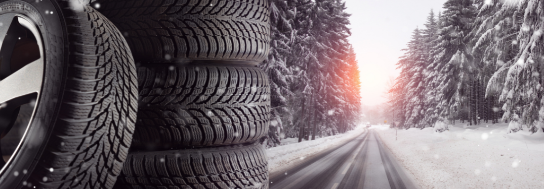 A stack of winter tires on a snowy road at sunset